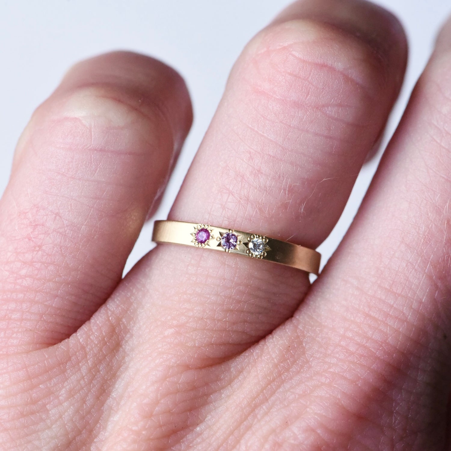 14k gold pink sapphire and diamond ombré ring shown on a hand, displaying the subtle satin finish and unique star-set stones by Corkie Bolton Jewelry.