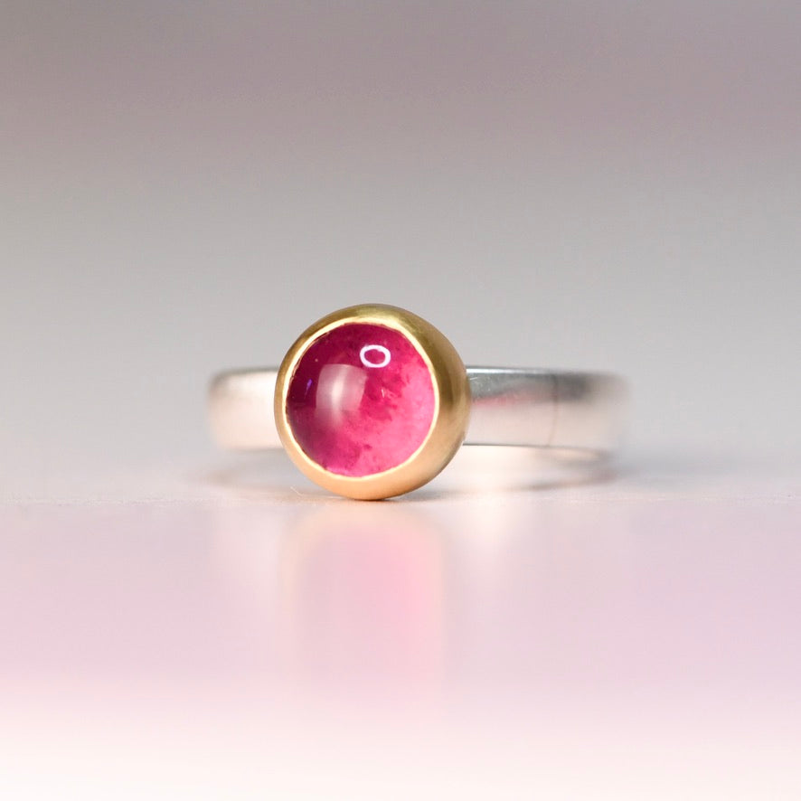 Side detail of a pink tourmaline cabochon set in a buttery 18k yellow gold bezel on a vintage sterling silver ring