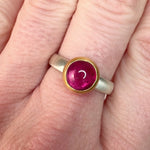 Video of a hand wearing a silver ring with a pink tourmaline cabochon set in 18k yellow gold.