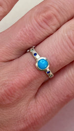 Video of handcrafted Sleeping Beauty turquoise and sapphire star ring in sterling silver rotating under natural light, made by Corkie Bolton Jewelry.