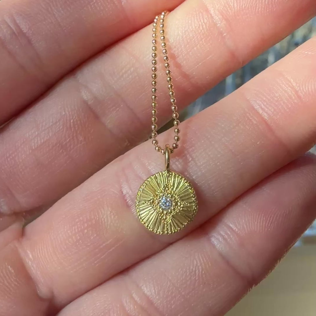 Close-up of the Reborn Engraved 18k Gold Charm, showcasing intricate hand-engraved details on the solid gold surface, hanging from a delicate chain.