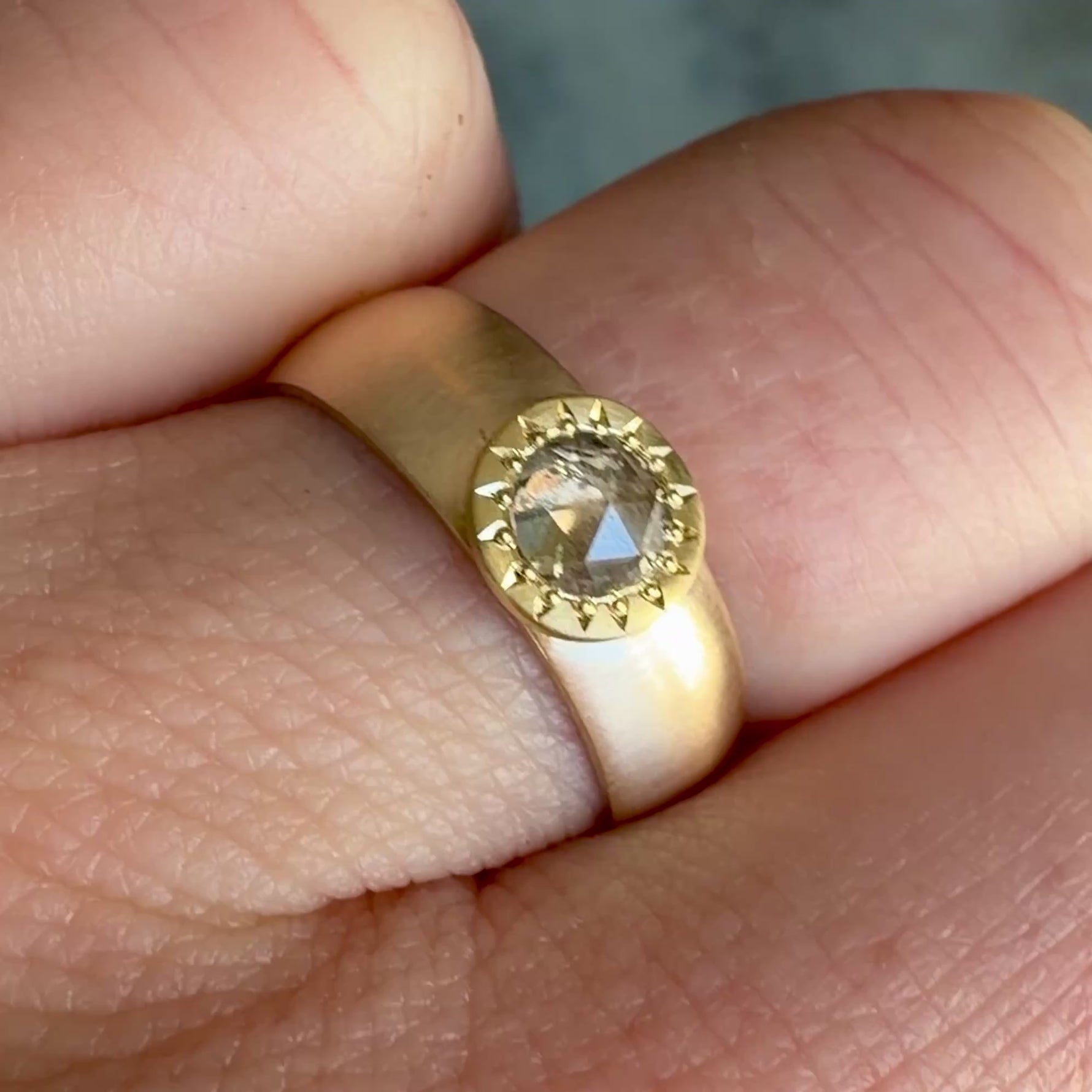 Video of a wide brushed 14k yellow gold ring with a hand-engraved 18k gold bezel set with a 0.40ct salt and pepper rose cut diamond, worn on a hand.