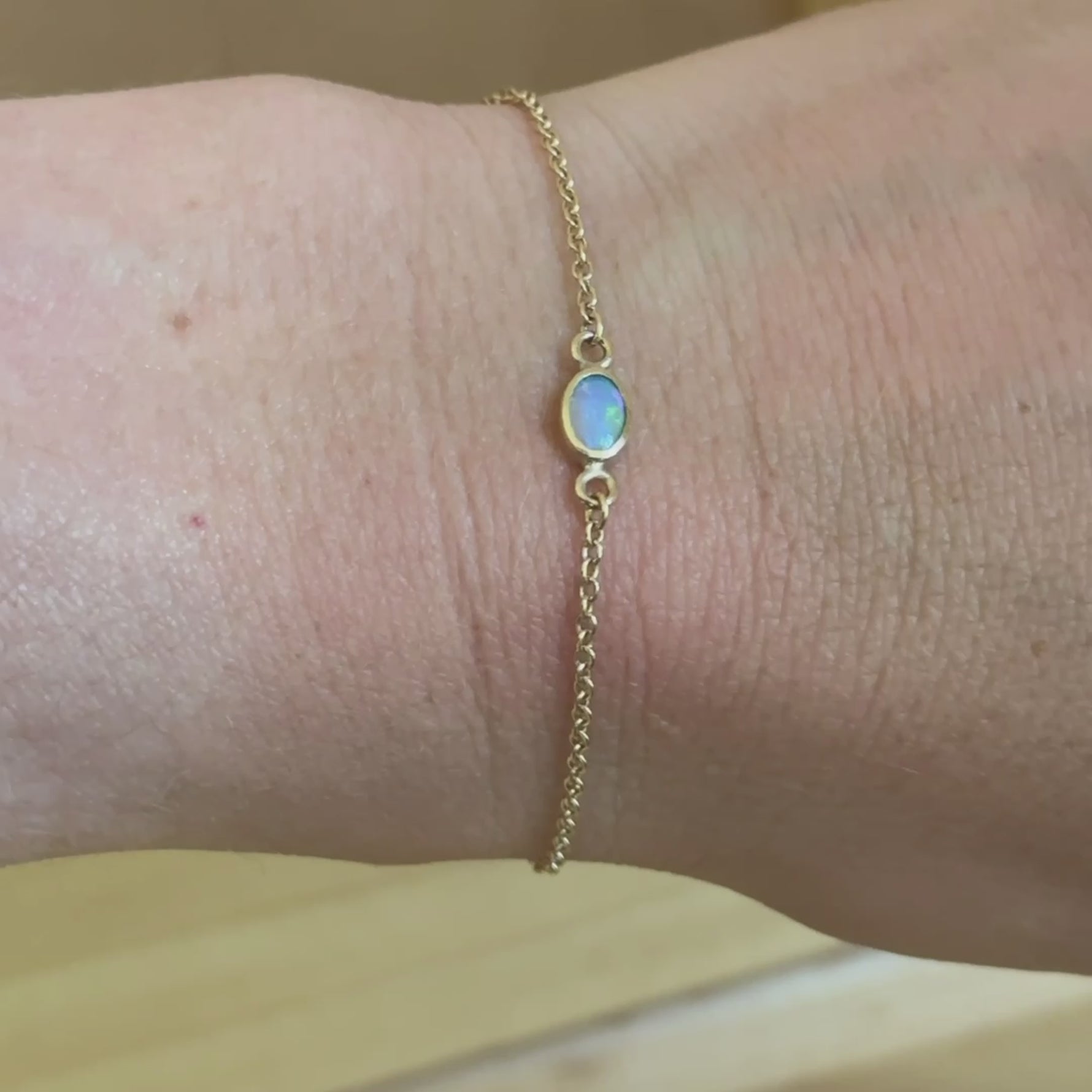 Wrist shot of the 14k gold opal chain bracelet, elegantly draped to highlight the opal’s iridescence and the bracelet’s dainty, timeless design.