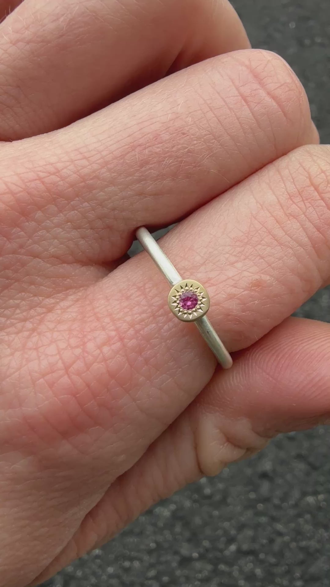 Pink sapphire stacking ring in 14k gold and sterling silver shown on hand, highlighting vibrant pink stone, satin band, and misfit-inspired design.