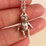 Hand holding a vintage sterling silver mid-century articulating teddy bear charm pendant by Corkie Bolton Jewelry