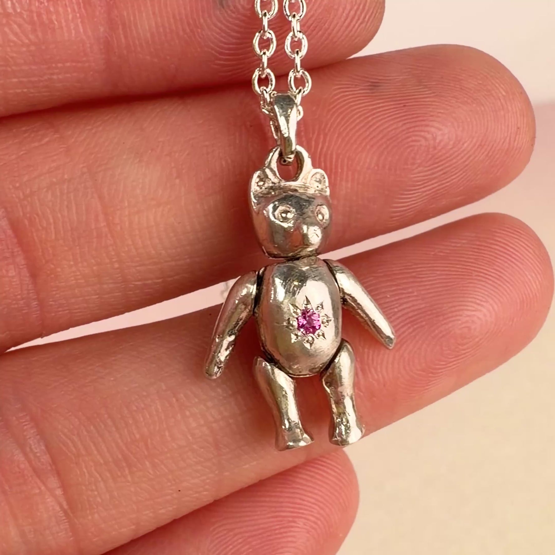 Hand holding a vintage sterling silver mid-century articulating teddy bear charm pendant by Corkie Bolton Jewelry
