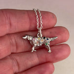 Video of a vintage mid-century sterling silver golden retriever charm with hand engraved star settings flush set with pink, purple, yellow, orange, red, and brown sapphires and colored diamonds held in a hand.