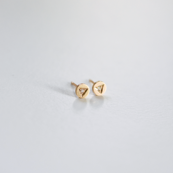 Hand engraved solid 14k yellow gold diamond stud earrings featuring a triangular setting and round stone.