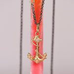 Vintage mid-century 18k yellow gold anchor and rope charm pendant with hand engraved star set white diamond hanging on an oxidized black rolo chain against a pink display stand, by Corkie Bolton Jewelry