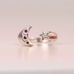 Vintage sterling silver open ring with crescent moon set with hand engraved purple pink and orange sapphires and orange diamond, and a star set with a yellow sapphire, displayed on a neutral surface by Corkie Bolton Jewelry