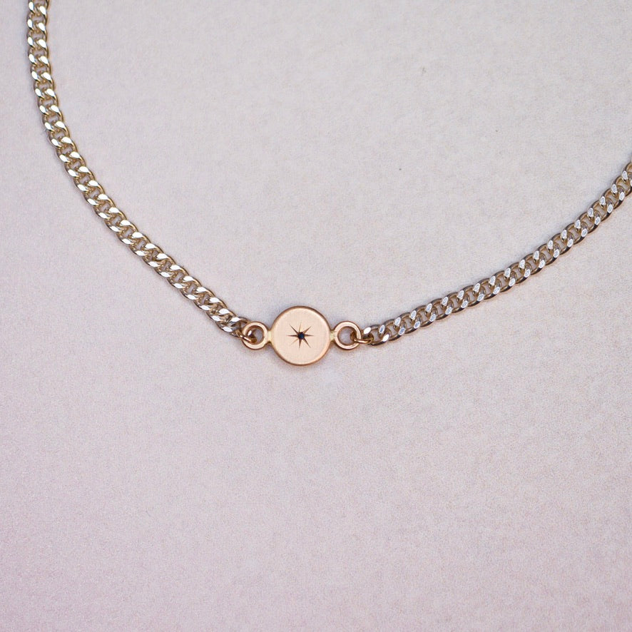 Reverse side of the 14k gold sapphire charm on the Vintage Curb Chain Bracelet, revealing engraved details on the back of the handcrafted 14k charm.