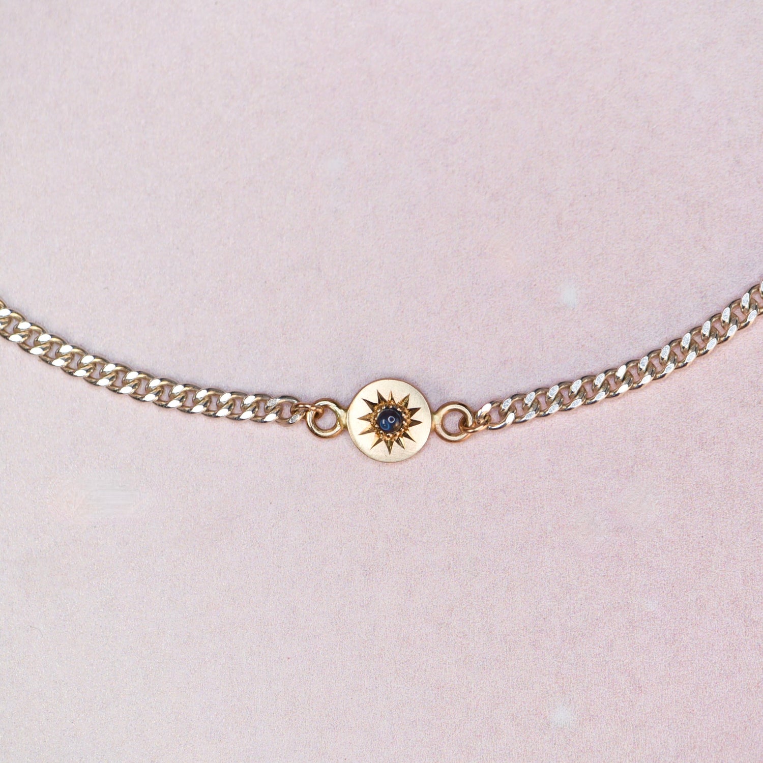 Close-up of the Vintage Curb Chain + 14k Sapphire Charm Bracelet by Corkie Bolton Jewelry, showing the blue sapphire cabochon set in a hand-engraved 14k gold star charm on a reclaimed silver curb chain.