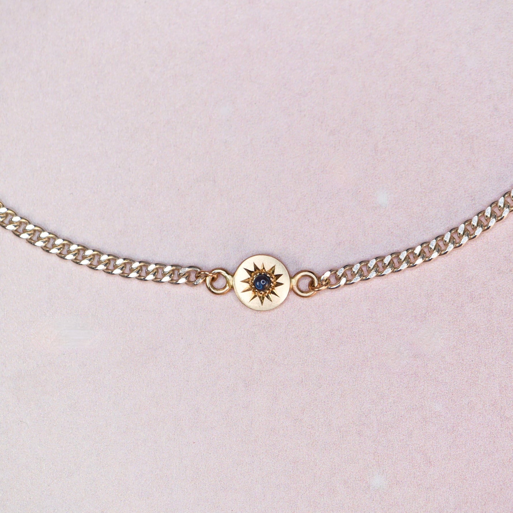 Close-up of the Vintage Curb Chain + 14k Sapphire Charm Bracelet by Corkie Bolton Jewelry, showing the blue sapphire cabochon set in a hand-engraved 14k gold star charm on a reclaimed silver curb chain.