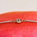 Gold bracelet with a blue gemstone on a red fabric background