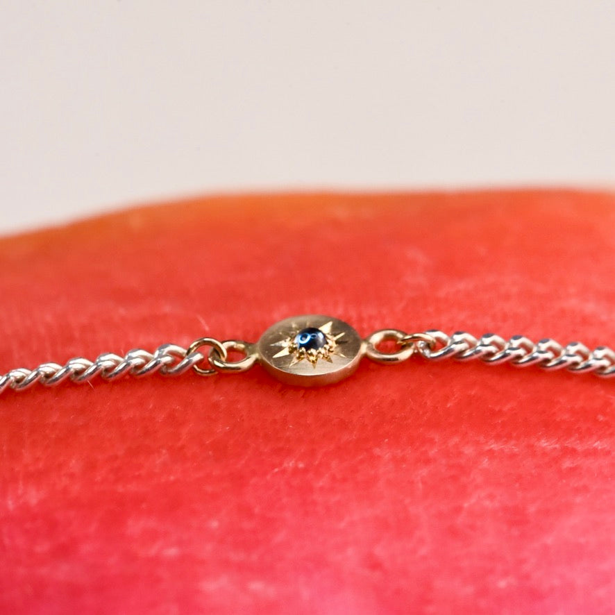 Gold bracelet with a blue gemstone on a red fabric background