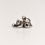 Side view of a vintage sterling silver Jezlaine kitten charm with detailed fur texture resting on a pink velvet surface