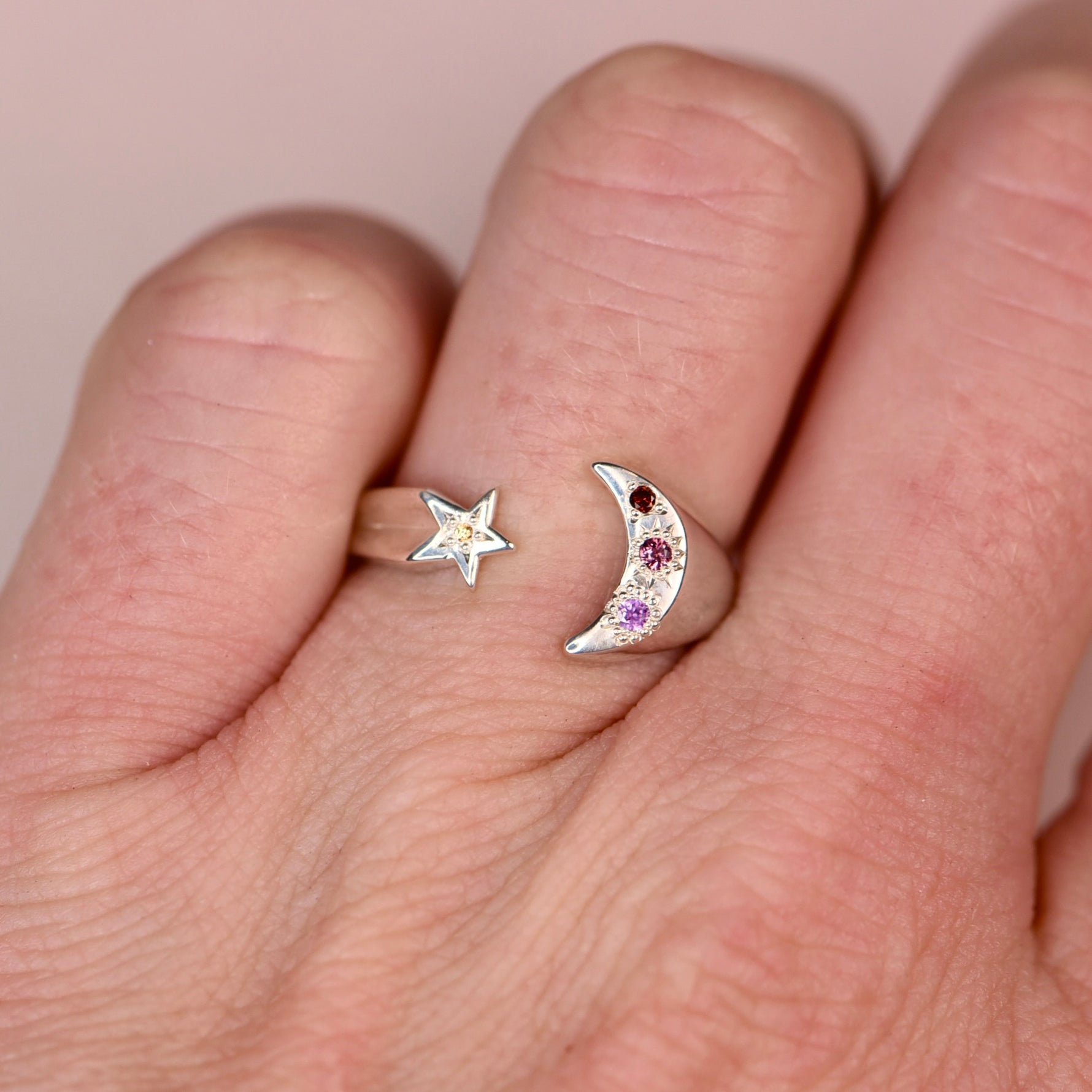 Vintage sterling silver open moon and star ring worn on a hand showing crescent moon with hand engraved purple pink and orange sapphires and orange diamond, and star with yellow sapphire, by Corkie Bolton Jewelry