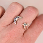 Vintage sterling silver open moon and star ring worn on a hand showing crescent moon with purple pink and orange sapphires and star with green rose-cut diamond by Corkie Bolton Jewelry
