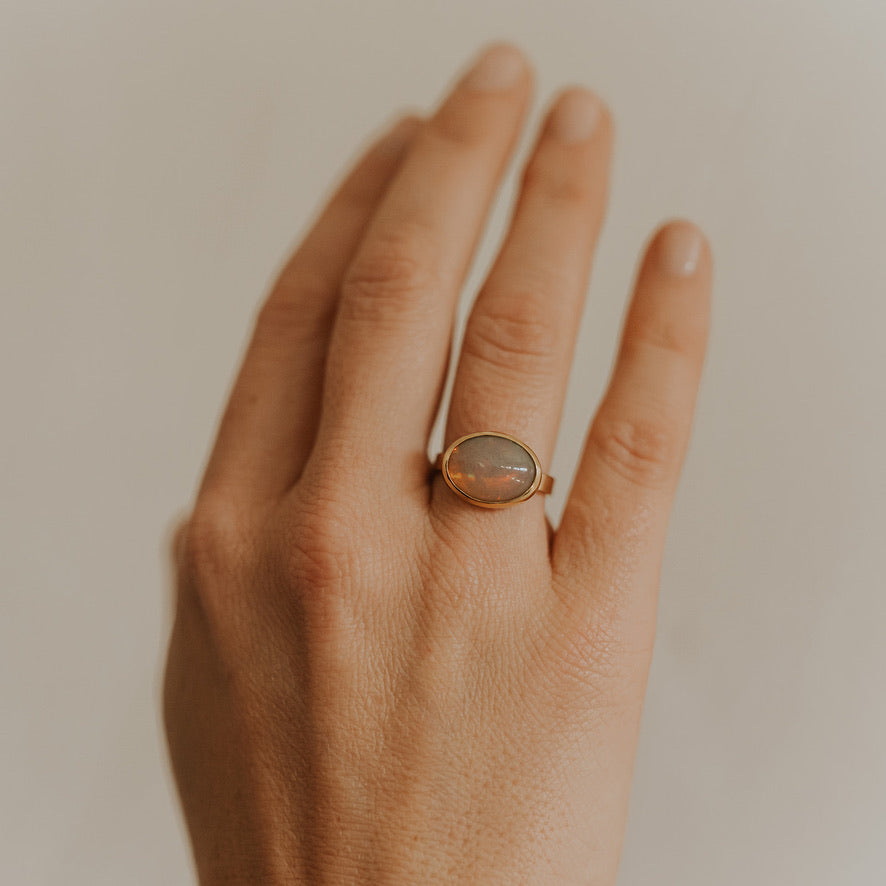 Hand wearing the 18k and 22k Gold Opal Ring, highlighting the size, colorful opal, and high-karat gold details.