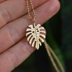 Image of the Gold Monstera Charm on a chain, close-up view: A solid 14k recycled gold Monstera charm with finely detailed leaves, shown hanging from a delicate gold chain.