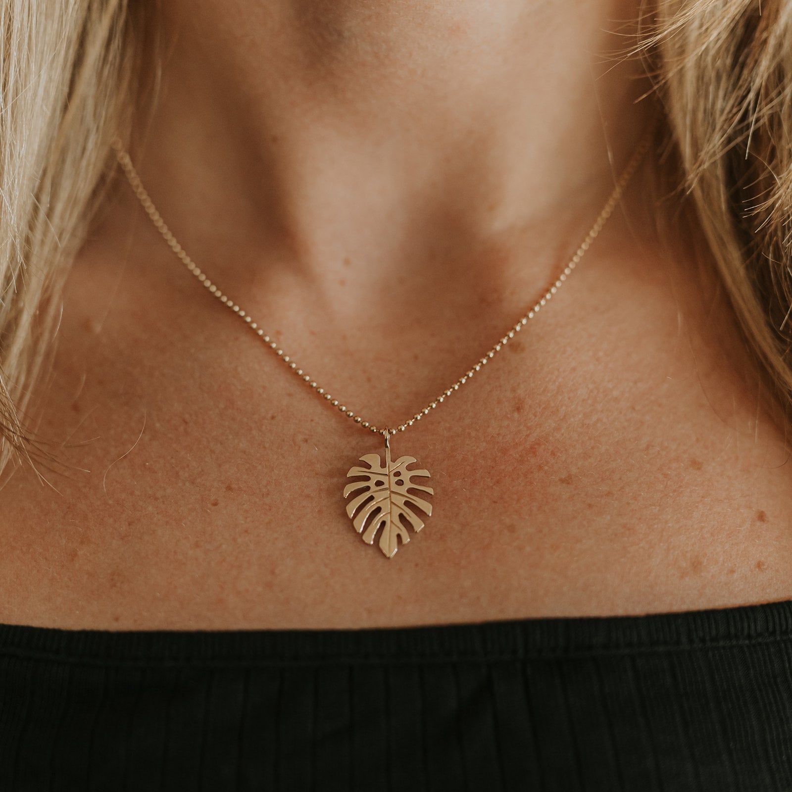 Image of the Gold Monstera Charm on a chain, close-up view: A solid 14k recycled gold Monstera charm with finely detailed leaves, shown hanging from a delicate gold chain.