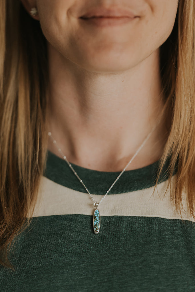 This gorgeous one of a kind necklace features an American Turquoise cabochon set in sterling silver with a tiny flower. Wear it on the included 18" beaded cable chain and evoke those first moments of spring!