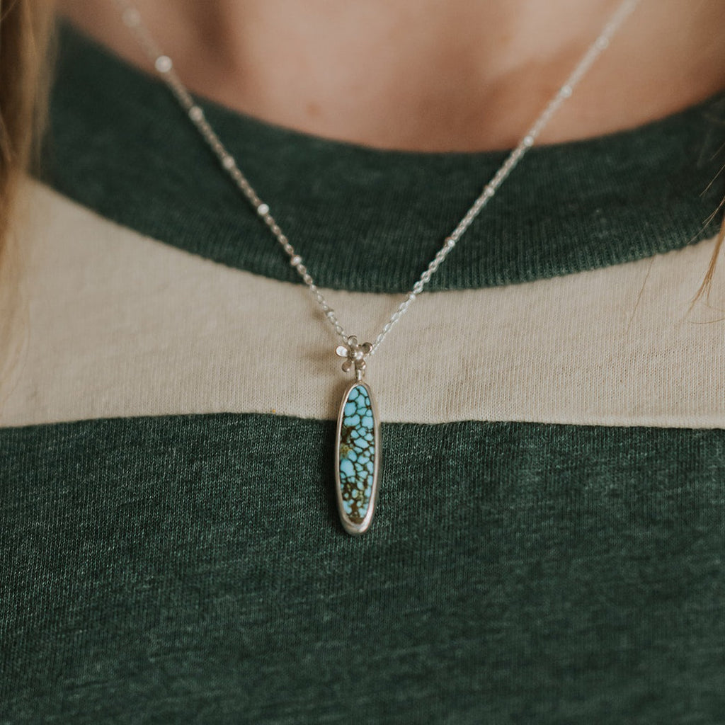 This gorgeous one of a kind necklace features an American Turquoise cabochon set in sterling silver with a tiny flower. Wear it on the included 18" beaded cable chain and evoke those first moments of spring!