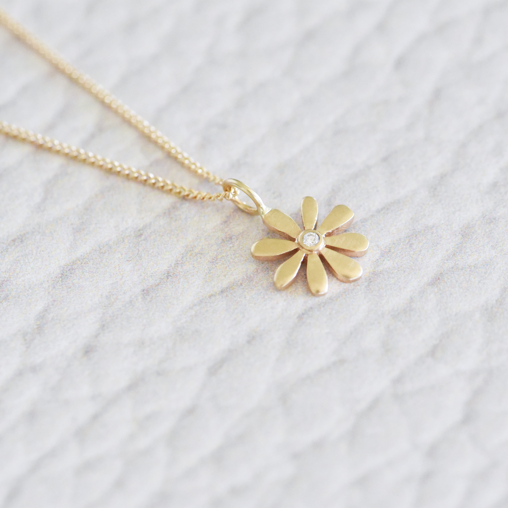 This retro-style, solid 14k yellow gold flower necklace is anything but subtle - sparkling with a small center diamond.