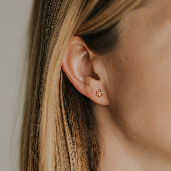 14k Yellow gold flower stud on an ear.